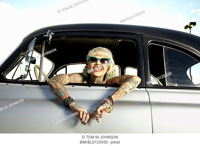 Woman with tattoos leaning out window of 1951 Chevy