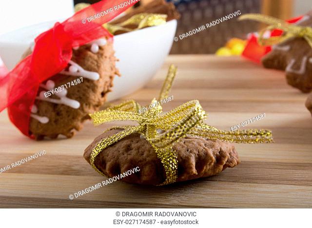 Decorating gingerbread cookies with colourfull ribbons on wooden plate