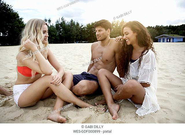Germany, Haltern, three friends sitting on the beach