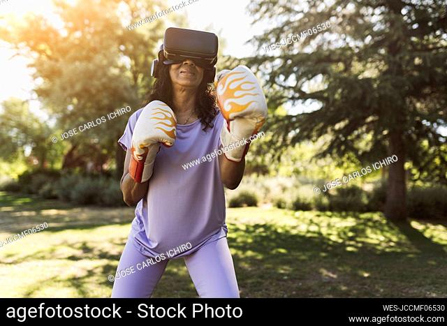 Elderly woman with VR Goggles boxing in public park