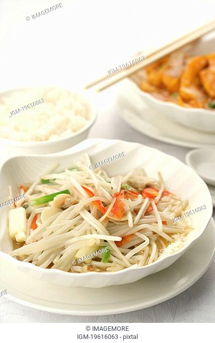 Cooked soybean sprout in white dish, a bowl of steamed rice, a plate of Chinese cuisine with chopsticks on it