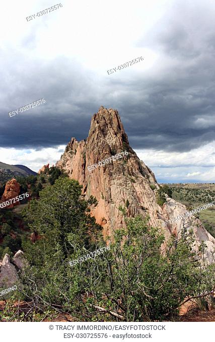 Rock formations and vegetation along a hiking trail at Garden of the Gods in Colorado Springs, Colorado, USA, under stormy skies