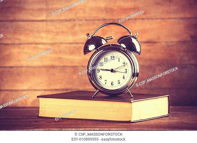 Alarm clock and book. Photo in old color image style