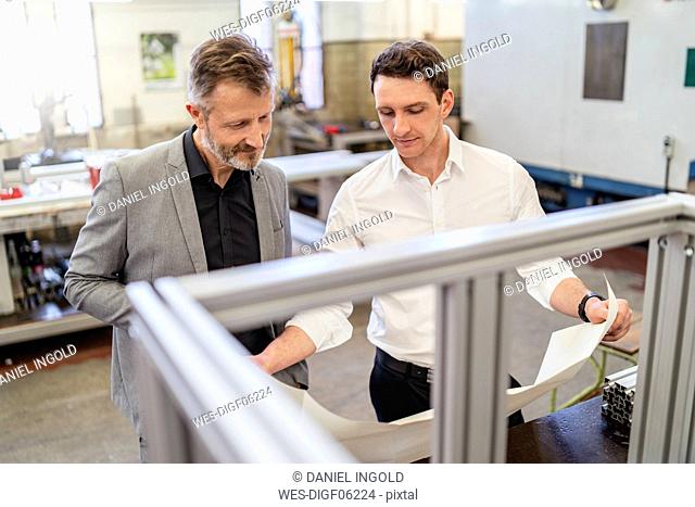 Two businessmen discussing plan in a factory