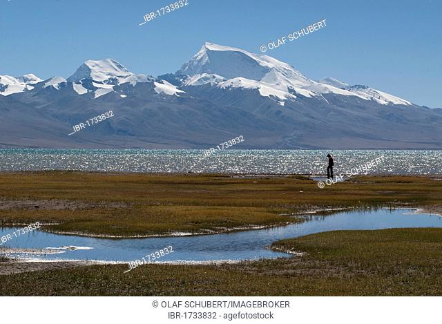 Man hiking in front of Mt Gurla Mandata, Gurla Mandhata, Naimo Na'nyi in Tibetan, 7728m, with the sacred Manasarovar Lake near the holy Mountain of Mount...