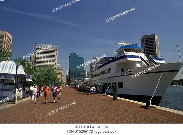 Baltimore, Inner Harbor, Maryland, People walk along the pier next to a tour boat on the Inner Harbor in Baltimore in the state of Maryland