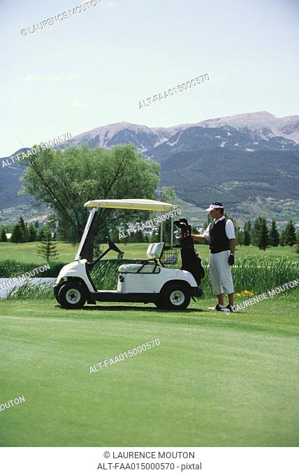 Golfer taking golf bag from golf cart