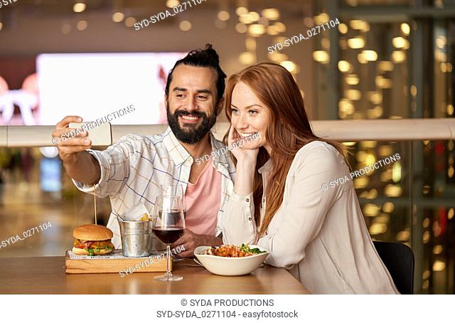 couple taking selfie by smartphone at restaurant