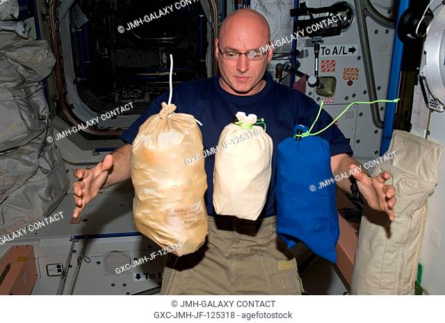 NASA astronaut Scott Kelly, Expedition 25 flight engineer, is pictured near three stowage bags floating freely in the Unity node of the International Space...