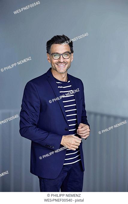 Portrait of smiling businessman with stubble wearing blue suit and glasses