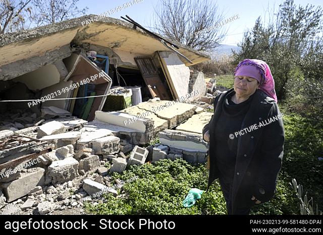 13 February 2023, Turkey, Ördekdede: A woman stands in front of the rubble of her house. In the small village, almost all the houses have collapsed or been...