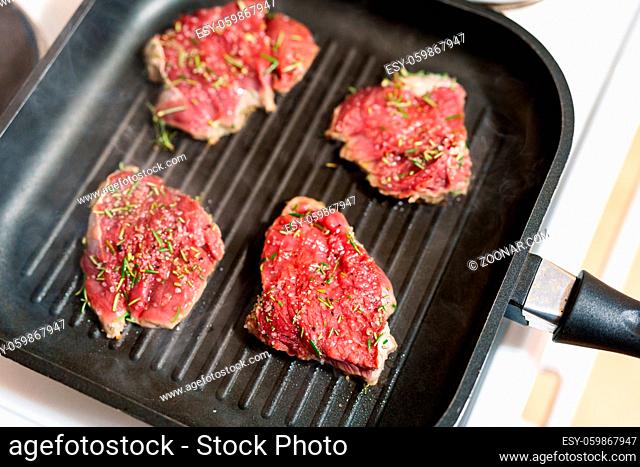 Four raw steaks are fried on a grilled pan. High quality photo