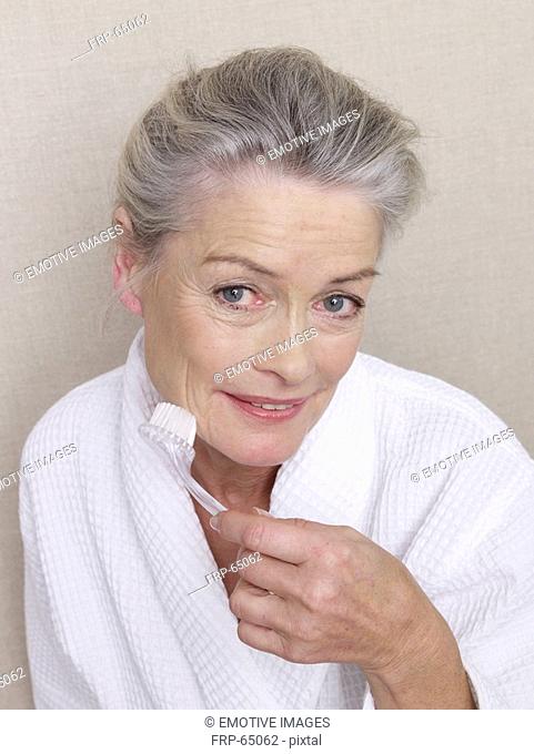 Senior adult in bathrobe using brush
