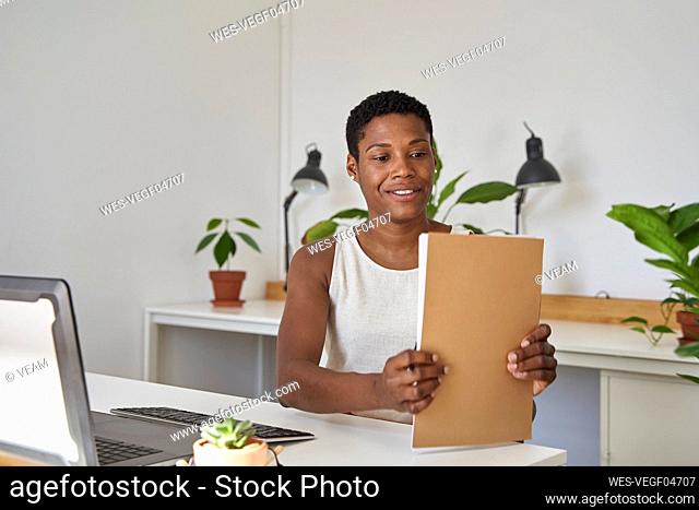 Businesswoman with short hair arranging file at desk