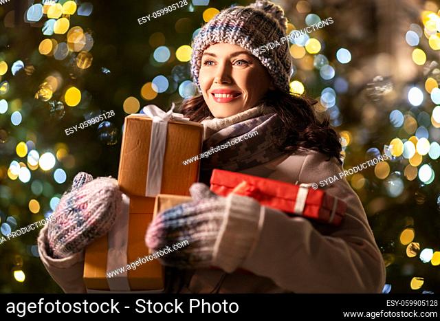 happy woman with christmas gifts over lights