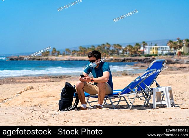 Tourism during pandemic. Safe traveling. Coronavirus travel ban. Quarantine due coronavirus epidemic. Sick tired young man in face mask sit on deck chair on...