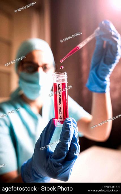 Conceptual image of a nurse using a pipette and a recipient with the coronavirus COVID-19 vaccine