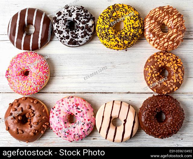 Top view of assorted donuts on a wooden background
