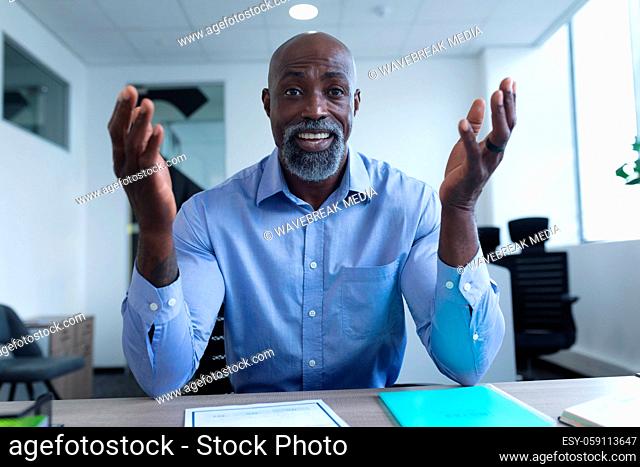 Portrait of african american businessman sitting at desk and having video call