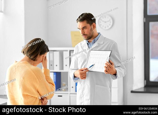 doctor showing cardiogram to sad woman at hospital