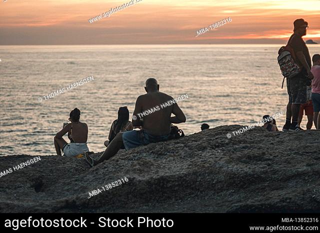 A magical place: People applaud when the sun sets at Arpoador rock with view of Ipanema beach and the Mountains of Morro Dois Irmaos and Leblon in the back