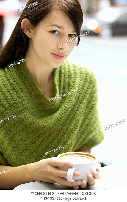 Beautiful young woman relaxing with her cappuccino outdoor