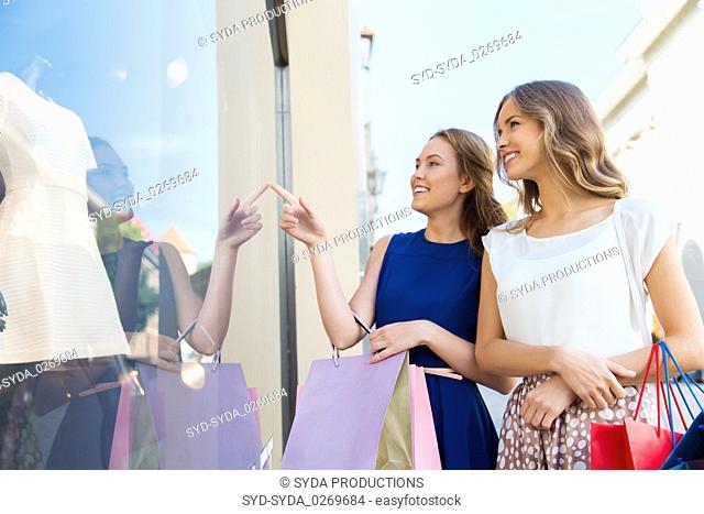 happy women with shopping bags at storefront