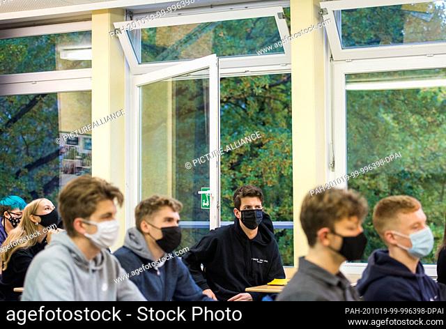 19 October 2020, Hamburg: Pupils of a 13th class of the upper school of the Niendorf district school sit with masks (mouth and nose covers) in front of an open...