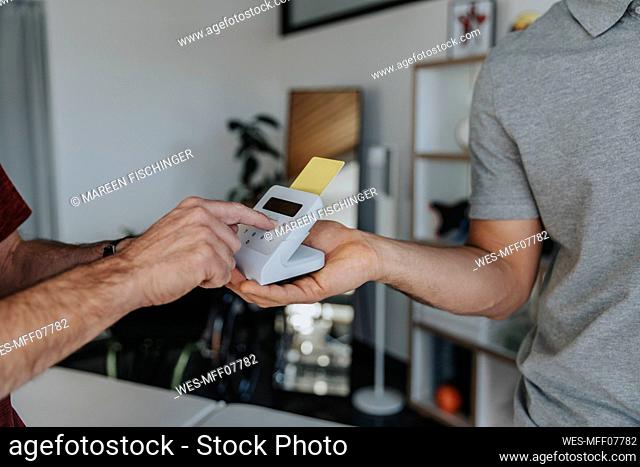 Patient entering pin in card reader in medical practice