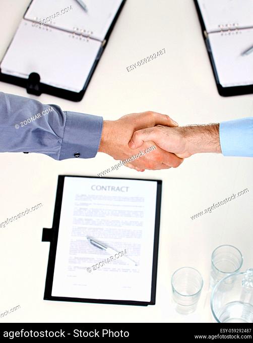 Closeup of hands, businessmen shaking hand over contract on meeting table in office