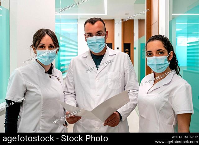 Doctor and nurses wearing protective face masks standing in corridor of hospital