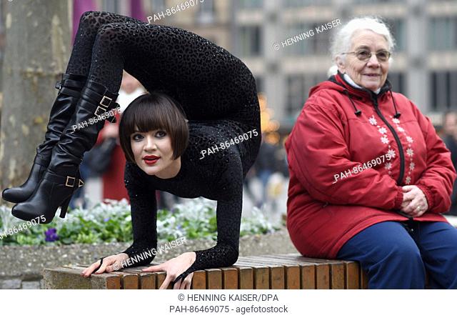 Contortionist Alina Ruppel shows off her skills beside a member of the public on a bench in Cologne, Germany, 12 December 2016
