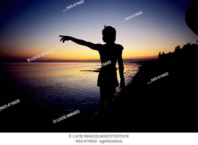 Woman pointing on beach at sunset. Visayas. Bohol. Philippines