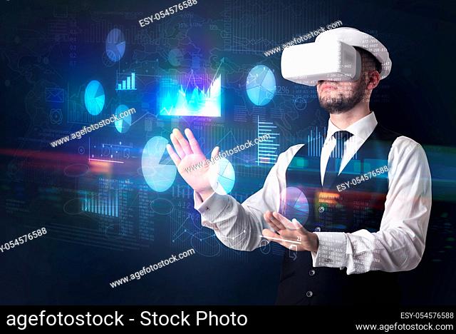 Elegant businessman in DJI goggles handling 3D reports and charts around him