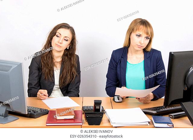 Two young pretty business woman sitting at a office table is divided into two jobs