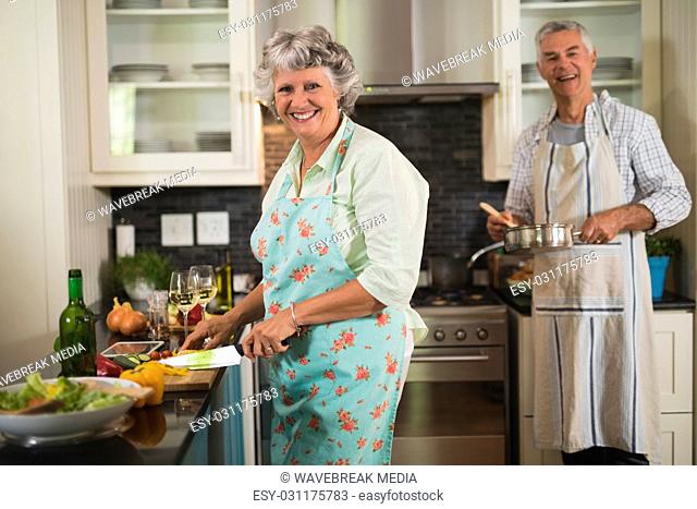 Smiling senior couple cooking in kitchen at home