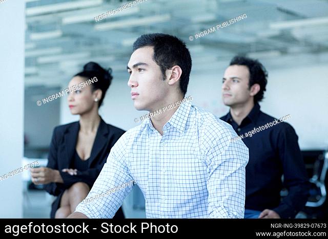 Three serious business people sitting in a business meeting