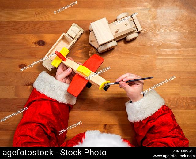 Santa Claus making toys. Painting and coloring wooden toy