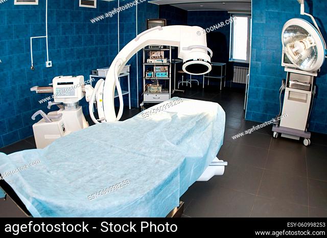 Blue modern operating room with X-ray medical scan, operating table with special lamp, medical devices. Research medical diagnosis and health care technology...