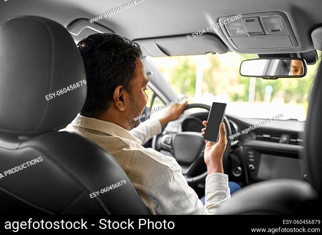 smiling indian man in car using smartphone