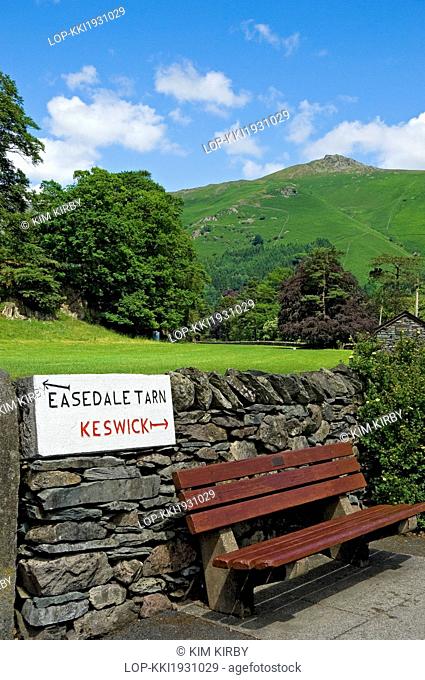 England, Cumbria, Grasmere. A hand carved sign with directions to Easedale Tarn and Keswick on a stone wall