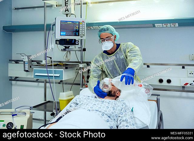 Doctor with bag valve mask caring for patient in emergency care unit of a hospital
