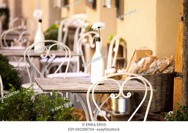 Cozy terrace on an italian street with white chairs and white flowers