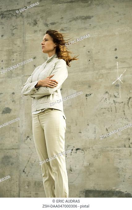 Woman with arms folded, deep in thought, looking away