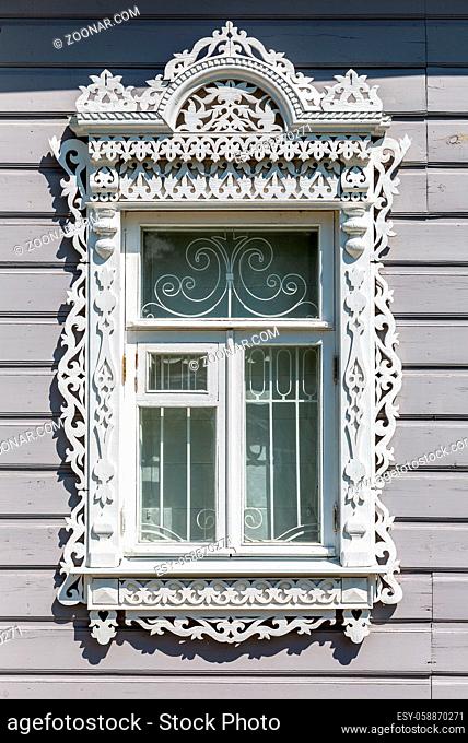 Russian traditional wooden architecture. Facade of an old house decorated with wooden carvings, platbands, wooden lace ornament