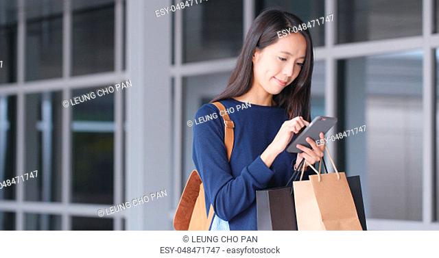 Woman use of mobile phone and shopping bag