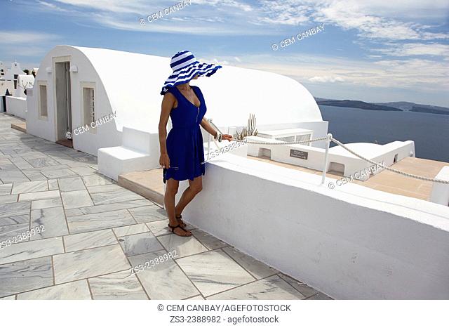 Woman in blue dress standing near a hotel entrance in Oia town, Santorini, Cyclades Islands, Greek Islands, Greece, Europe