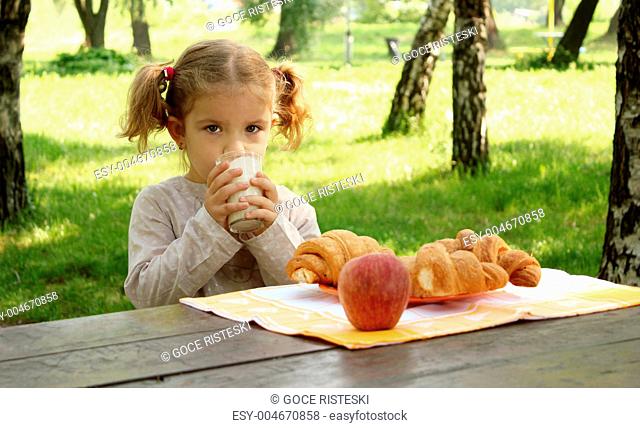 young girl drink milk in park