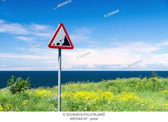 Precipice edge warning sign. Danger sea cliff hidden by grass and flowers
