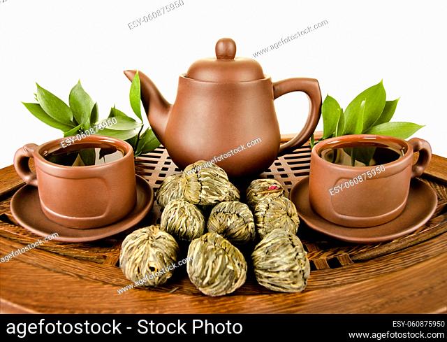 still life of the clay teapot and cup on wooden trivet, on white background, isolated